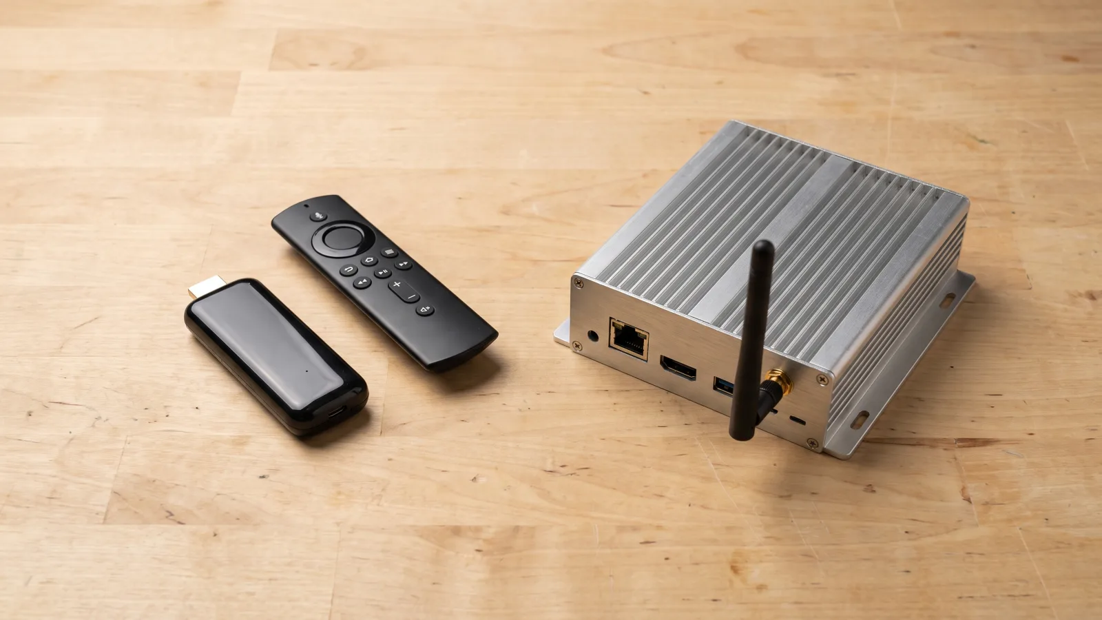 Consumer Android TV stick next to a fanless commercial Android media player, showing the size and build difference between the two device classes