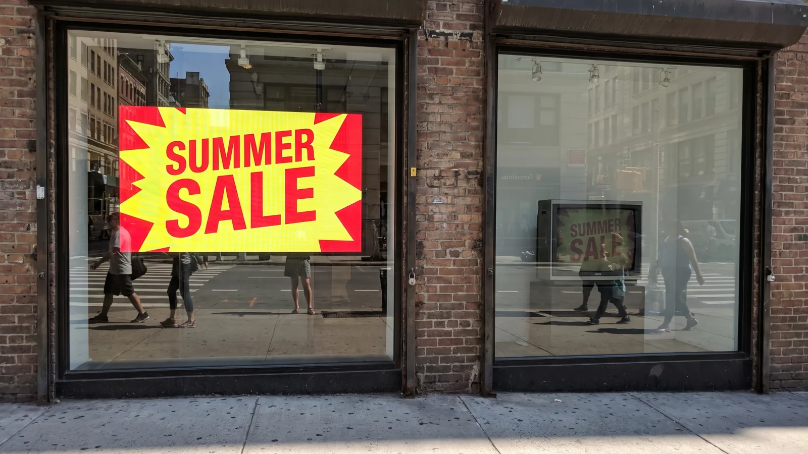 High-brightness Samsung OM window display staying readable in a sunlit storefront next to a washed-out consumer TV