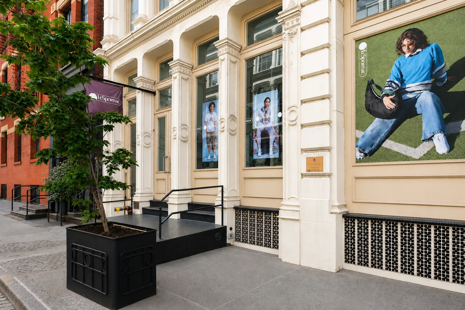 LeSportsac SoHo flagship storefront at 32 Greene Street, window displays and a campaign wall graphic visible along the sidewalk