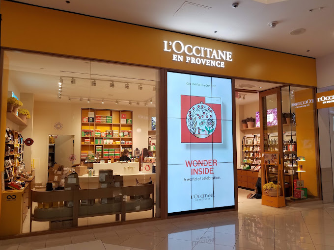 L’Occitane store entrance with a large vertical digital screen displaying “Wonder Inside” campaign artwork.