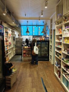 Deli counter with multiple digital menu boards displaying breakfast, sandwiches, salads, and sides.