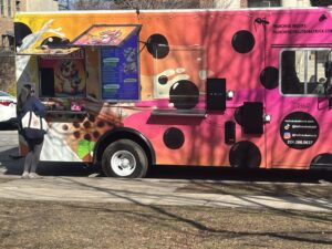 Side of Hello Boba truck showing service windows, large black dots, and contact/branding graphics.