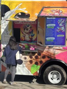Close view of boba truck window with unicorn illustration, menu board, and customer ordering.