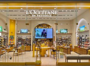 Wide storefront interior view with signage and a large video wall in back.