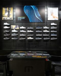 Shoe display wall with shelves and a large digital screen showing product promotion.