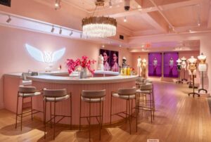 Pink-themed pop-up interior with bar seating, neon wings sign, and mannequins.