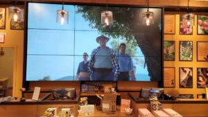 Large video wall behind checkout showing brand video content in a retail store.
