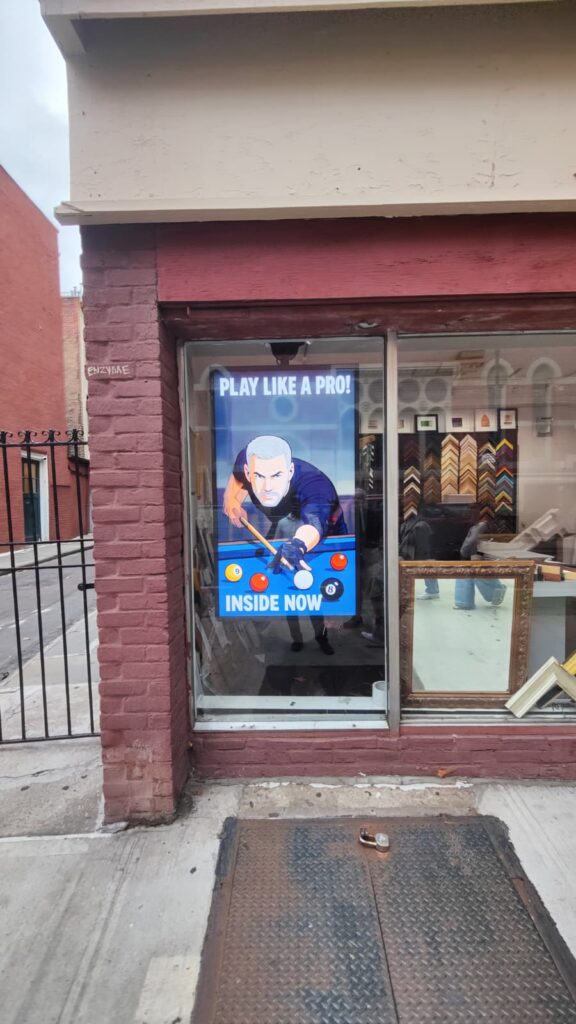 Sunlight-readable window display attracting pedestrians with bold, high-contrast promotion.